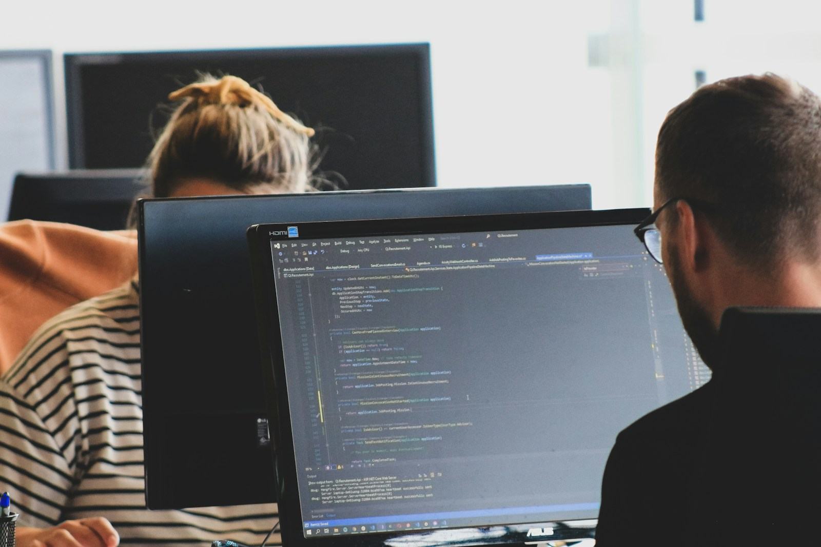 Equipo de ingeniería trabajando frente a monitores con código
