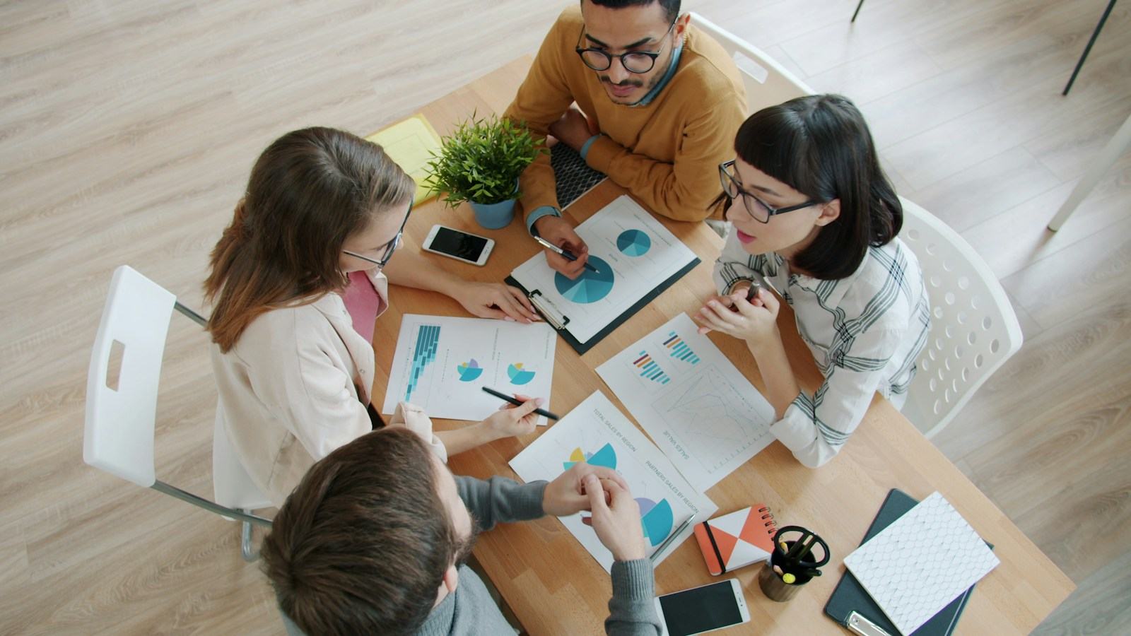 Vista cenital de un equipo analizando gráficos sobre una mesa